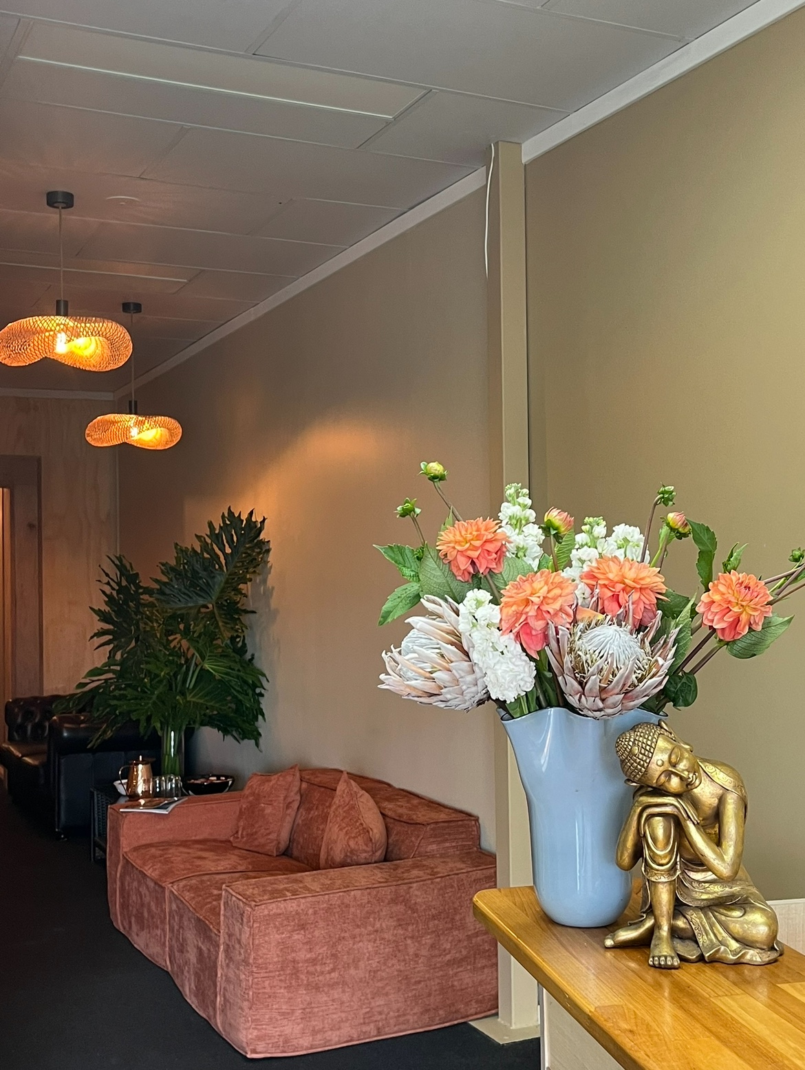 Aviano lounge space with native floral bouquet and brass Buddha sculpture
