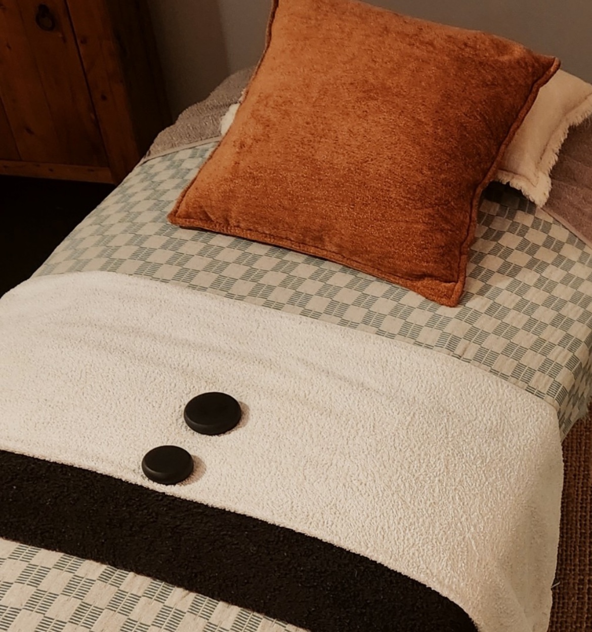 Treatment bed with heated basalt stones and tactile terracotta velvet pillow